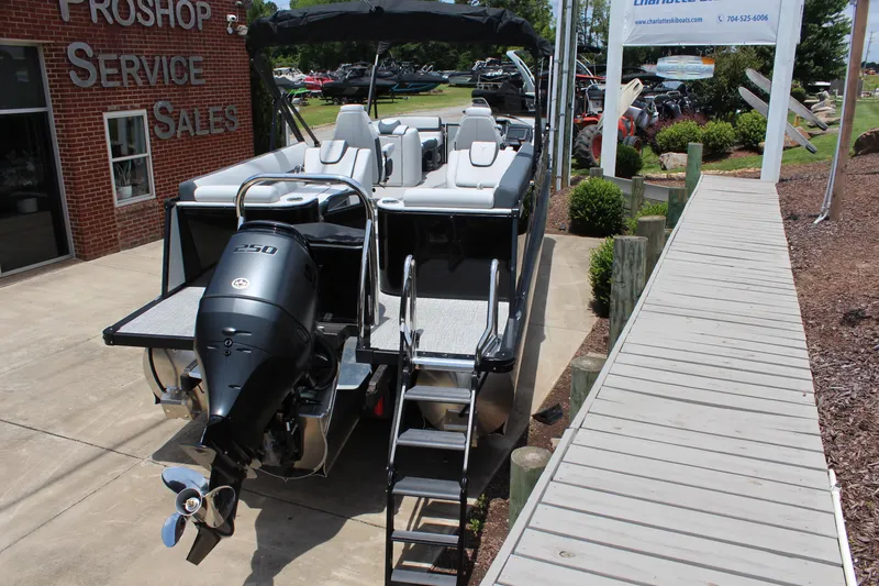 Slide: The Image of 2025 Tahoe Pontoon Cascade Quad Lounger at dealership, rear view with outboard motor. - 4