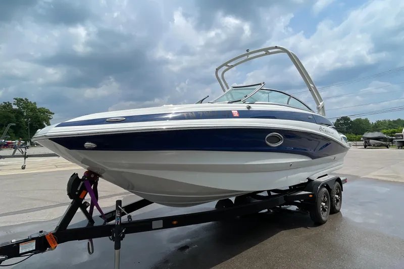 The Image of 2023 Crownline E235 boat on trailer under cloudy sky. - 1