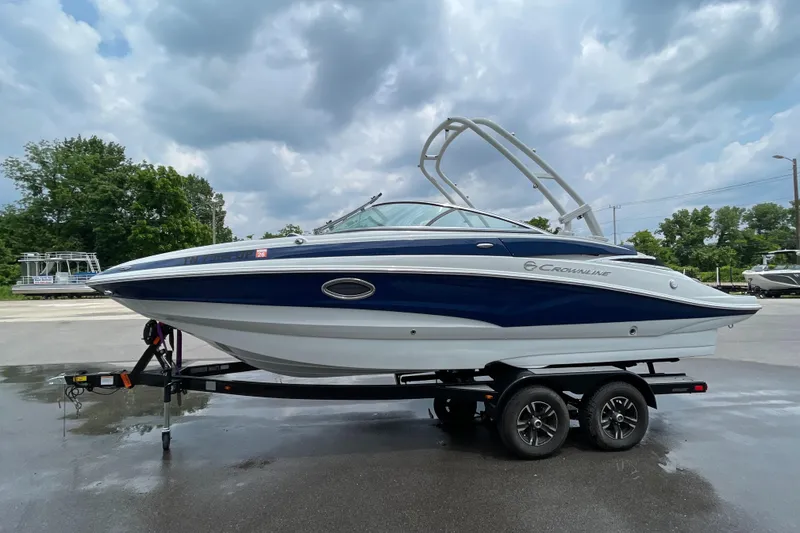 Slide: The Image of 2023 Crownline E235 boat on trailer under cloudy sky. - 2