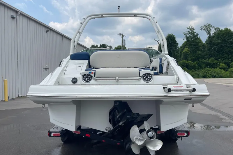 Slide: The Image of 2023 Crownline E235 boat, rear view, showcasing propeller and seating, parked outdoors. - 3