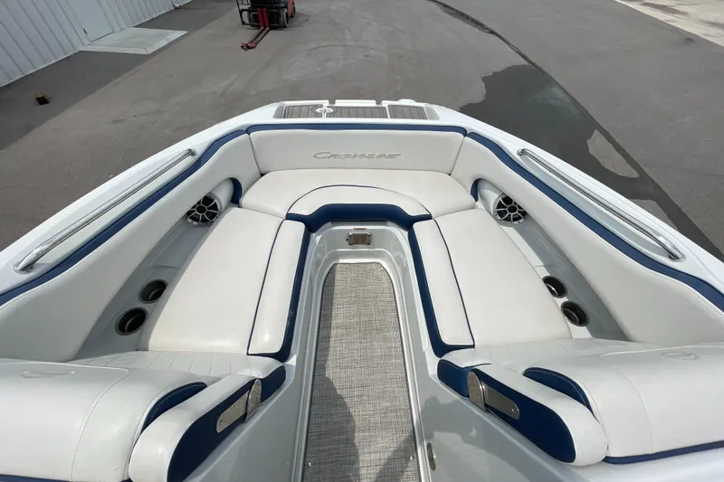 Slide: The Image of 2023 Crownline E235 boat interior with white and blue seating, featuring cup holders and speakers. - 6