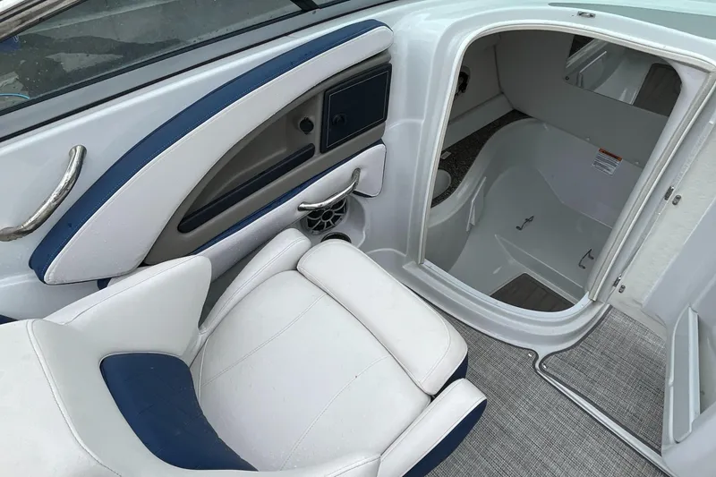 Slide: The Image of 2023 Crownline E235 boat interior with white and blue seating and open cabin door. - 8