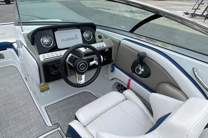 Slide: The Image of 2023 Crownline E235 boat interior with Garmin navigation, steering wheel, and comfortable seating. - 9