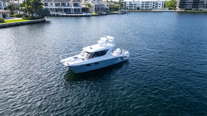 Slide: The Image of 2023 ArrowCat Flybridge Dual Helm boat on calm water near waterfront homes. - 10