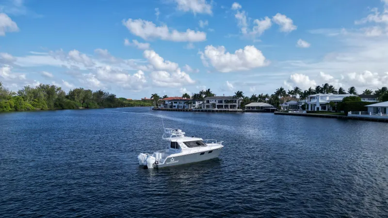 Slide: The Image of 2023 ArrowCat Flybridge Dual Helm boat on a serene waterfront with luxury homes. - 15