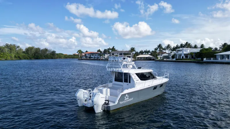 Slide: The Image of 2023 ArrowCat Flybridge Dual Helm boat on a serene waterway with luxury homes. - 16