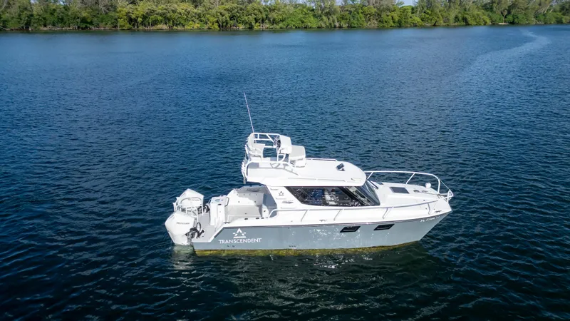 Slide: The Image of 2023 ArrowCat Flybridge Dual Helm boat on a serene lake. - 2