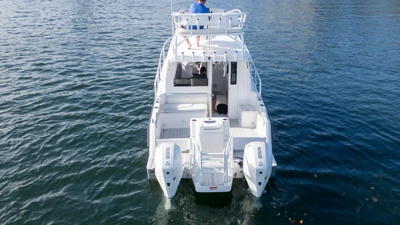 Slide: The Image of 2023 ArrowCat Flybridge Dual Helm boat on water, rear view, with dual outboard engines. - 20