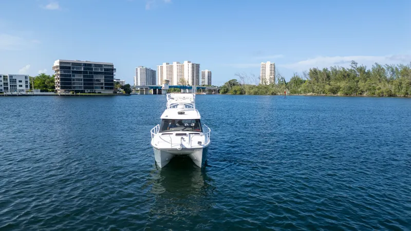 Slide: The Image of 2023 ArrowCat Flybridge Dual Helm boat on calm water with cityscape background. - 7
