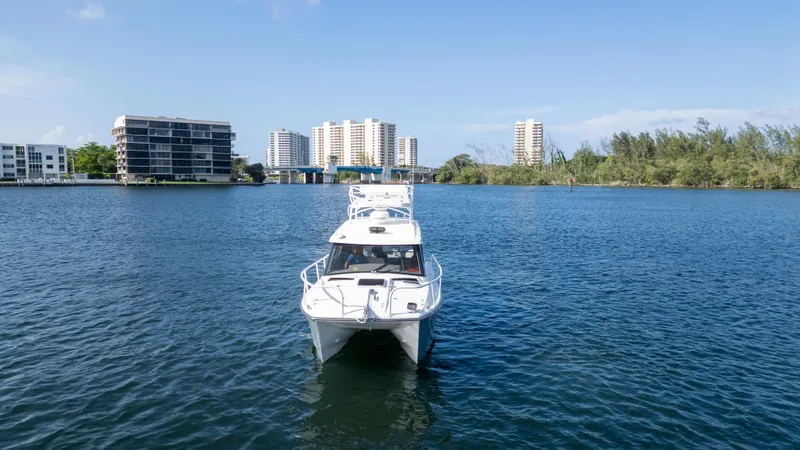 Slide: The Image of 2023 ArrowCat Flybridge Dual Helm boat on a serene waterway with cityscape backdrop. - 8