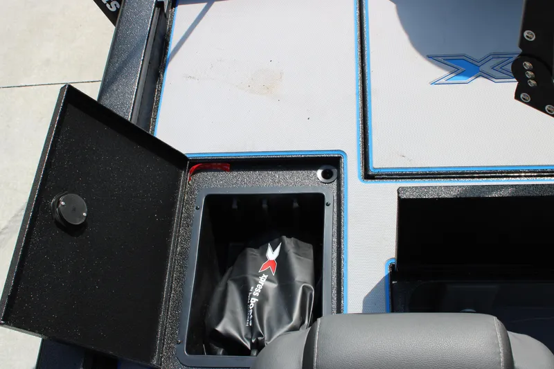 Slide: The Image of 2026 Xpress H18C Crappie boat storage compartment with black interior and branded bag. - 12