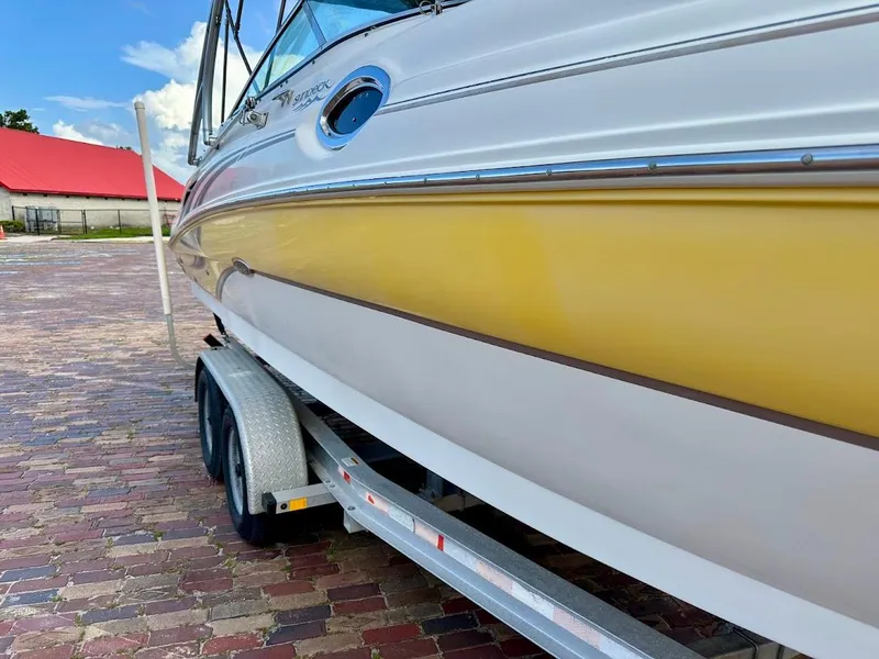 Slide: The Image of 2004 Sea Ray SUNDECK 270 boat on trailer, yellow and white exterior, parked on brick pavement. - 11