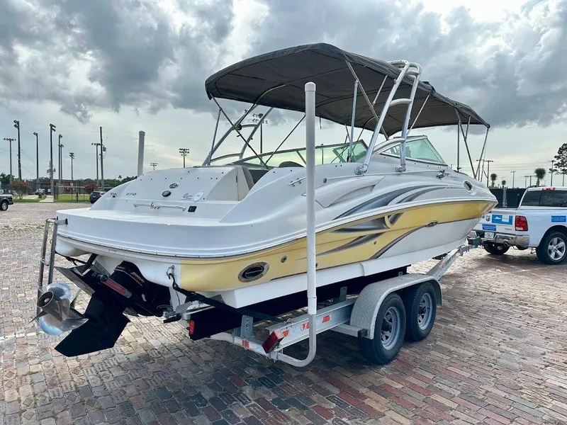 Slide: The Image of 2004 Sea Ray SUNDECK 270 boat on trailer, parked on brick pavement under cloudy sky. - 3
