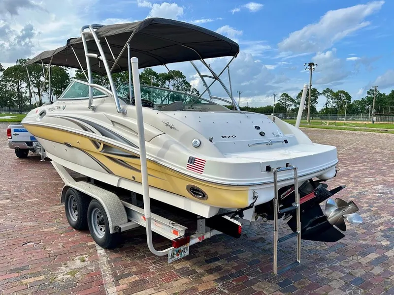 Slide: The Image of 2004 Sea Ray SUNDECK 270 boat on trailer, parked on brick pavement under a blue sky. - 4