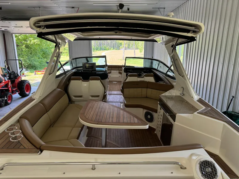 Slide: The Image of 2015 Sea Ray 350 SLX boat interior with brown seating and wooden table in a garage. - 10