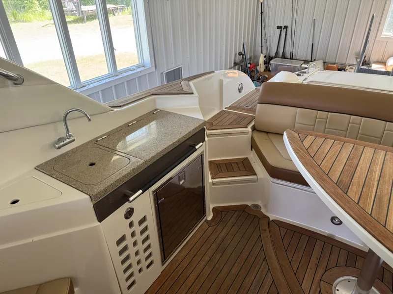 Slide: The Image of 2015 Sea Ray 350 SLX boat interior with kitchenette, seating, and wooden flooring. - 24