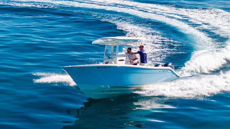 Slide: The Image of 2022 Cobia 240 CC boat cruising on clear blue water. - 0