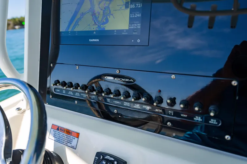 Slide: The Image of Control panel of 2022 Cobia 240 CC boat with navigation display and switches. - 15