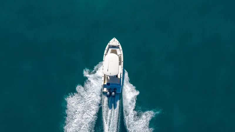 Slide: The Image of Aerial view of 2022 Cobia 240 CC boat cruising on clear blue water. - 30