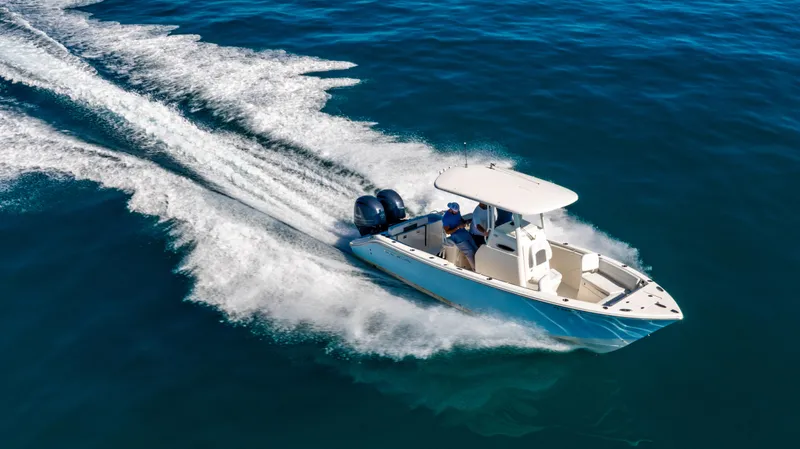 Slide: The Image of 2022 Cobia 240 CC boat cruising on open water, creating a dynamic wake. - 32