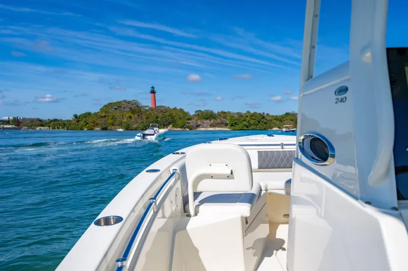 Slide: The Image of 2022 Cobia 240 CC boat cruising near a lighthouse on a sunny day. - 8