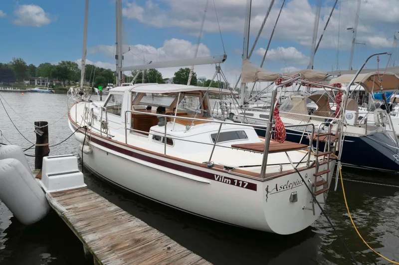 Slide: The Image of Sailboat Vilm 117, 2006 model, docked at a marina under a partly cloudy sky. - 1