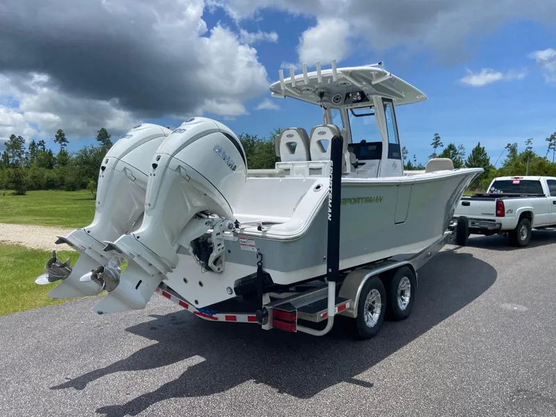 Slide: The Image of 2025 Sportsman Open 262 Center Console boat on trailer, dual engines, parked on road. - 3