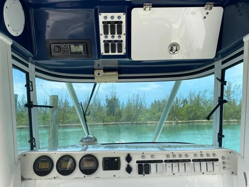 Slide: The Image of 2006 Everglades 260 CC boat dashboard with gauges and controls, overlooking serene water and trees. - 8