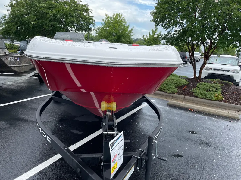 Slide: The Image of 2025 Tahoe T18 boat in parking lot, red hull, on trailer, surrounded by trees. - 1