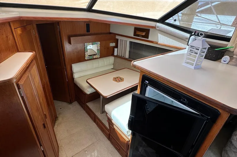 Slide: The Image of 1988 Carver 38 Aft Cabin interior with dining area, wood accents, and compact kitchen. - 17