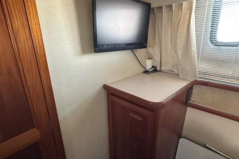 Slide: The Image of 1988 Carver 38 Aft Cabin interior with TV, wooden cabinetry, and window with curtains. - 32