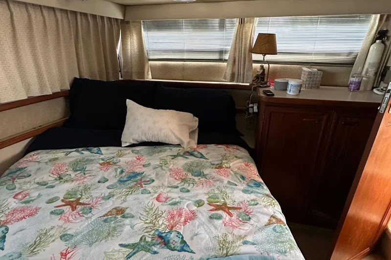 Slide: The Image of 1988 Carver 38 Aft Cabin bedroom with colorful bedding and wooden cabinetry. - 35
