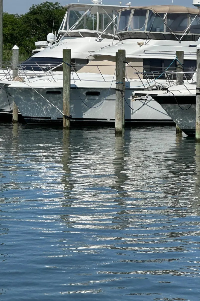 Slide: The Image of 1988 Carver 38 Aft Cabin yacht docked at marina, reflecting on calm water. - 4
