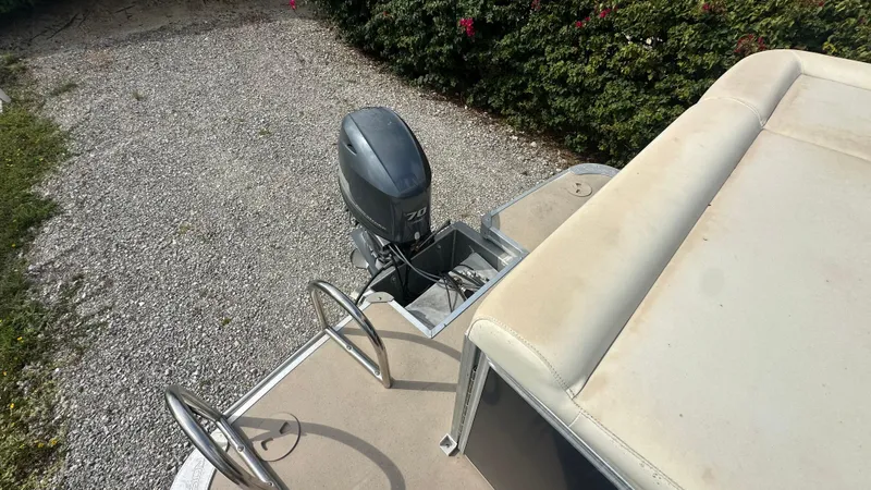 Slide: The Image of 2012 Xcursion X21C boat with outboard motor and seating, parked on gravel. - 4