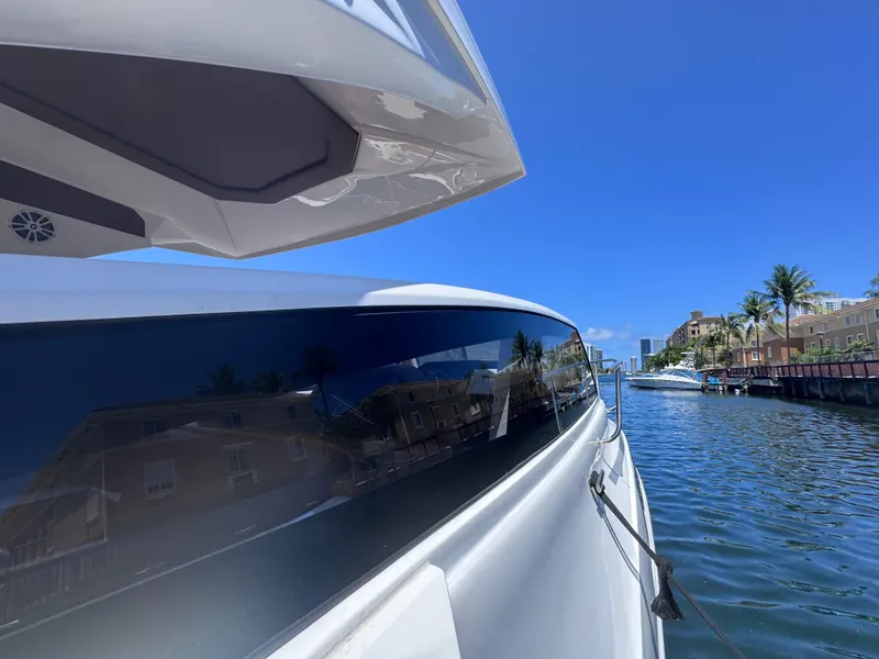 Slide: The Image of 2024 NX Boats 340 Sport Coupe on a sunny waterway, showcasing sleek design and modern features. - 11