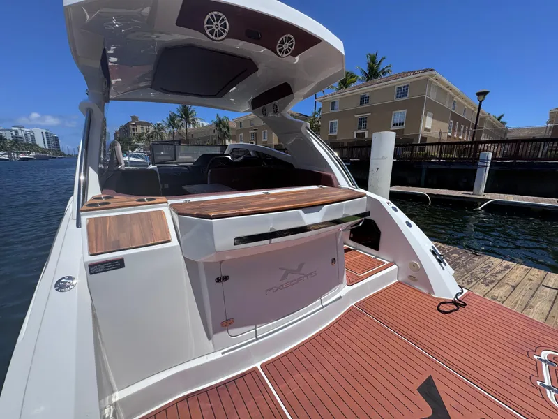 Slide: The Image of 2024 NX Boats 340 Sport Coupe docked, showcasing sleek design and spacious deck. - 13