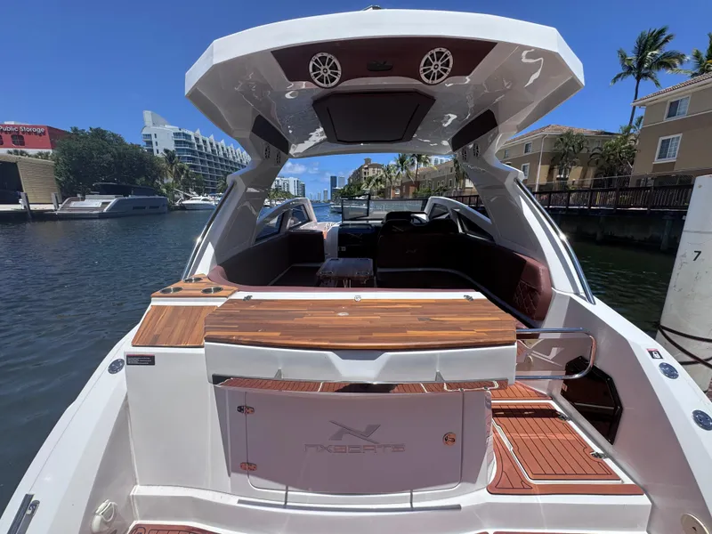 Slide: The Image of 2024 NX Boats 340 Sport Coupe docked, showcasing sleek design and luxurious interior. - 14