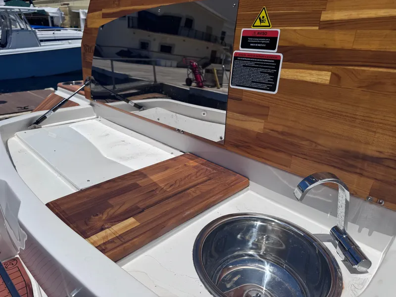 Slide: The Image of 2024 NX Boats 340 Sport Coupe kitchen area with wooden countertop and stainless steel sink. - 19