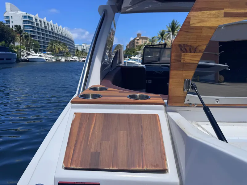 Slide: The Image of 2024 NX Boats 340 Sport Coupe on water, featuring sleek wooden accents and cup holders. - 20