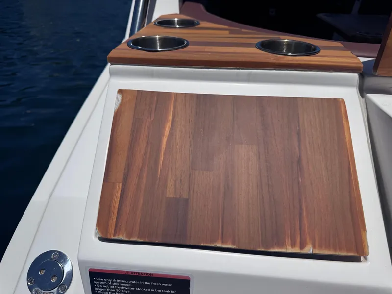 Slide: The Image of 2024 NX Boats 340 Sport Coupe wooden deck with cup holders, close-up view. - 21