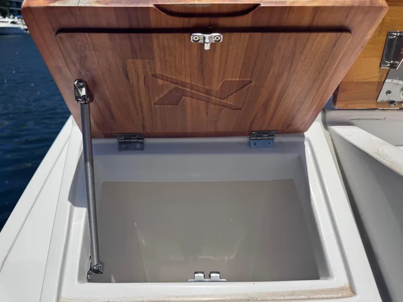 Slide: The Image of Open storage compartment on 2024 NX Boats 340 Sport Coupe with wooden lid. - 22