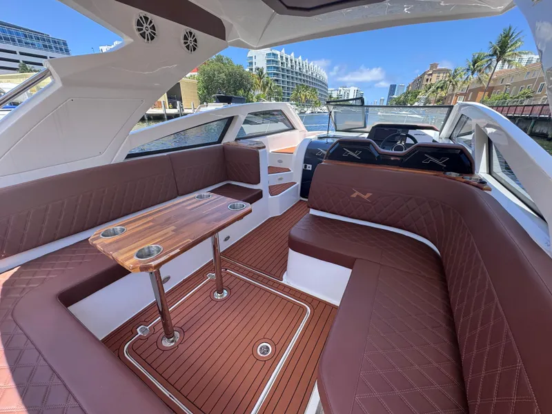 Slide: The Image of 2024 NX Boats 340 Sport Coupe interior with luxurious seating and wooden table. - 26