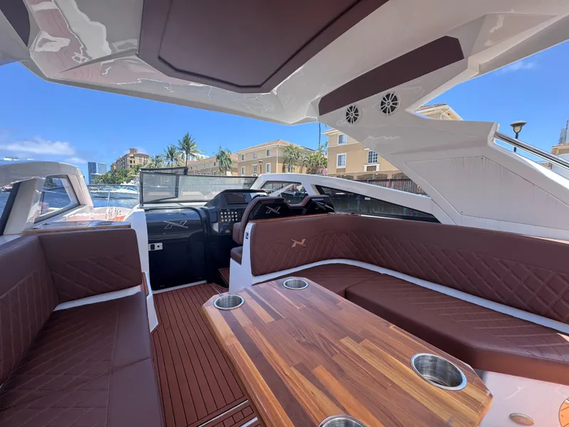 Slide: The Image of 2024 NX Boats 340 Sport Coupe interior with luxurious seating and wooden table. - 27