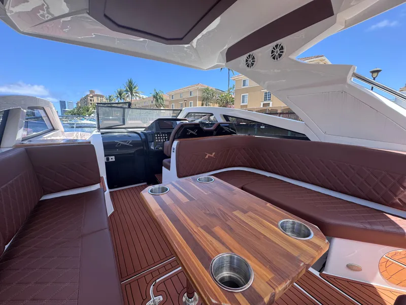 Slide: The Image of 2024 NX Boats 340 Sport Coupe interior with luxurious seating and wooden table. - 28