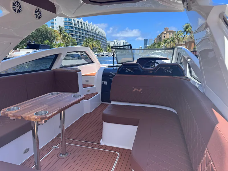Slide: The Image of 2024 NX Boats 340 Sport Coupe interior with luxurious seating and wooden table. - 29