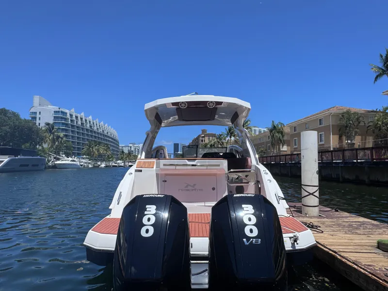 Slide: The Image of 2024 NX Boats 340 Sport Coupe docked, featuring dual 300 V8 engines, under clear blue sky. - 3