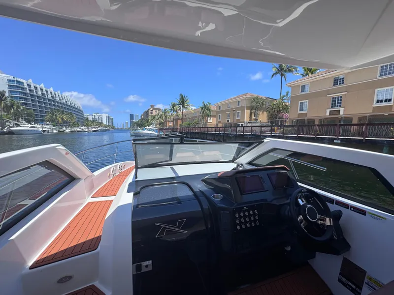 Slide: The Image of 2024 NX Boats 340 Sport Coupe on a sunny waterfront, showcasing modern helm and sleek design. - 31