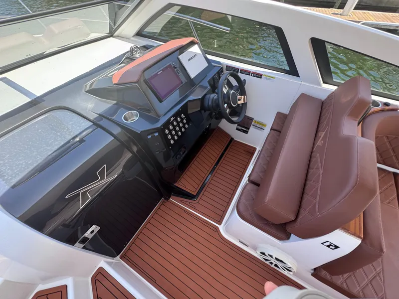 Slide: The Image of 2024 NX Boats 340 Sport Coupe cockpit with modern controls and brown leather seating. - 32