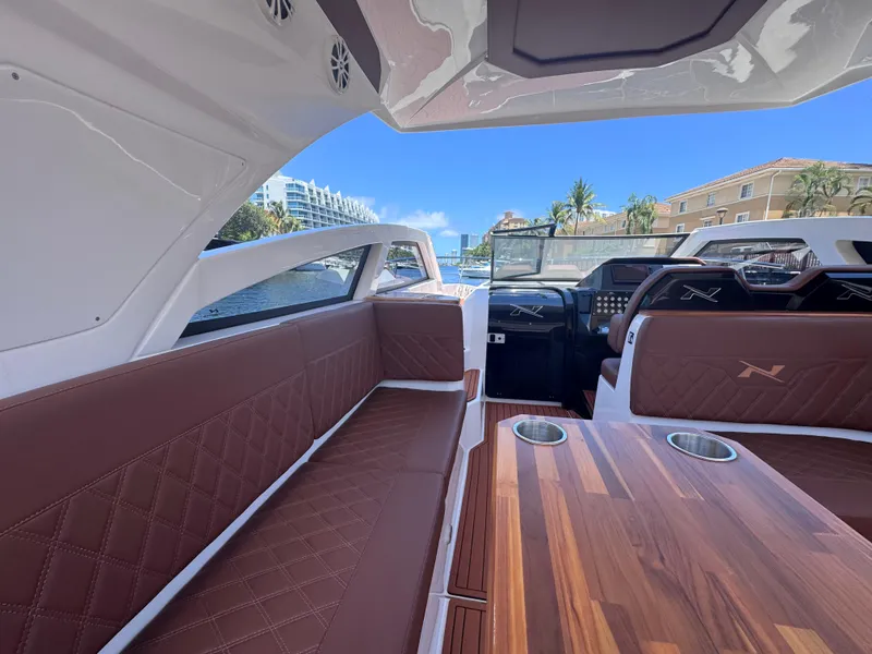 Slide: The Image of 2024 NX Boats 340 Sport Coupe interior with luxurious seating and wooden table. - 36