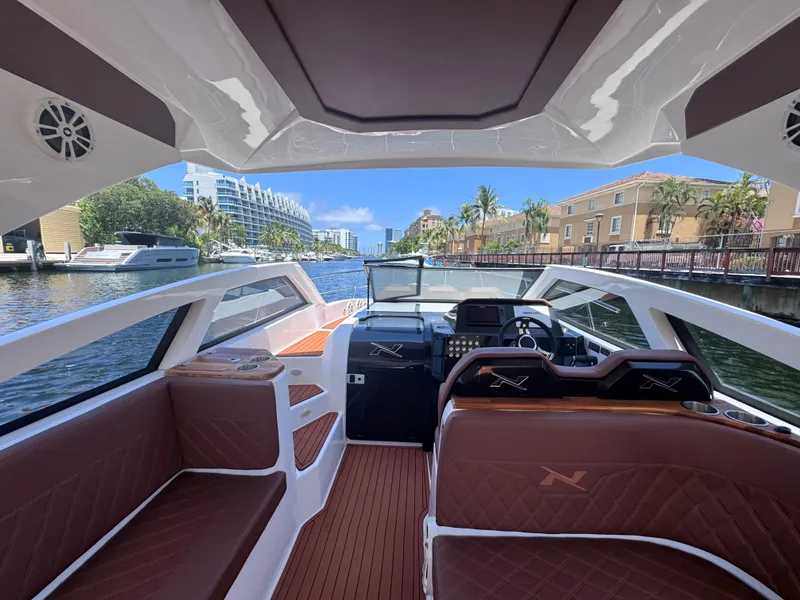 Slide: The Image of 2024 NX Boats 340 Sport Coupe interior with luxurious seating and modern dashboard on a scenic waterway. - 38